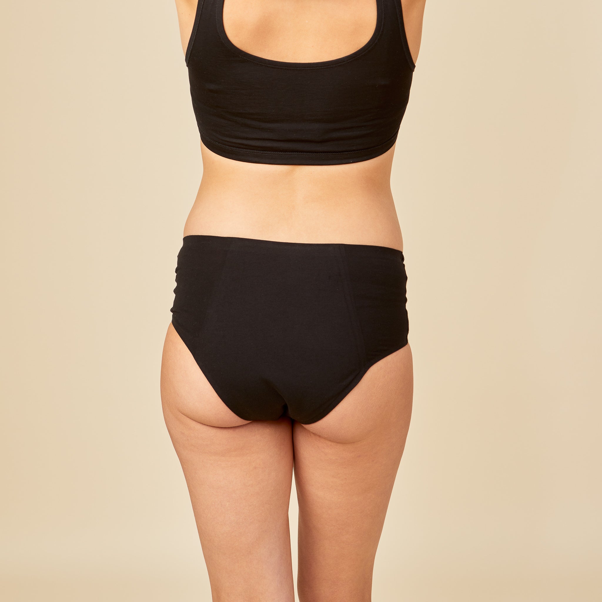 dais maternity absorbent underwear in high waist cut in black. Shown on pregnant model from the back.