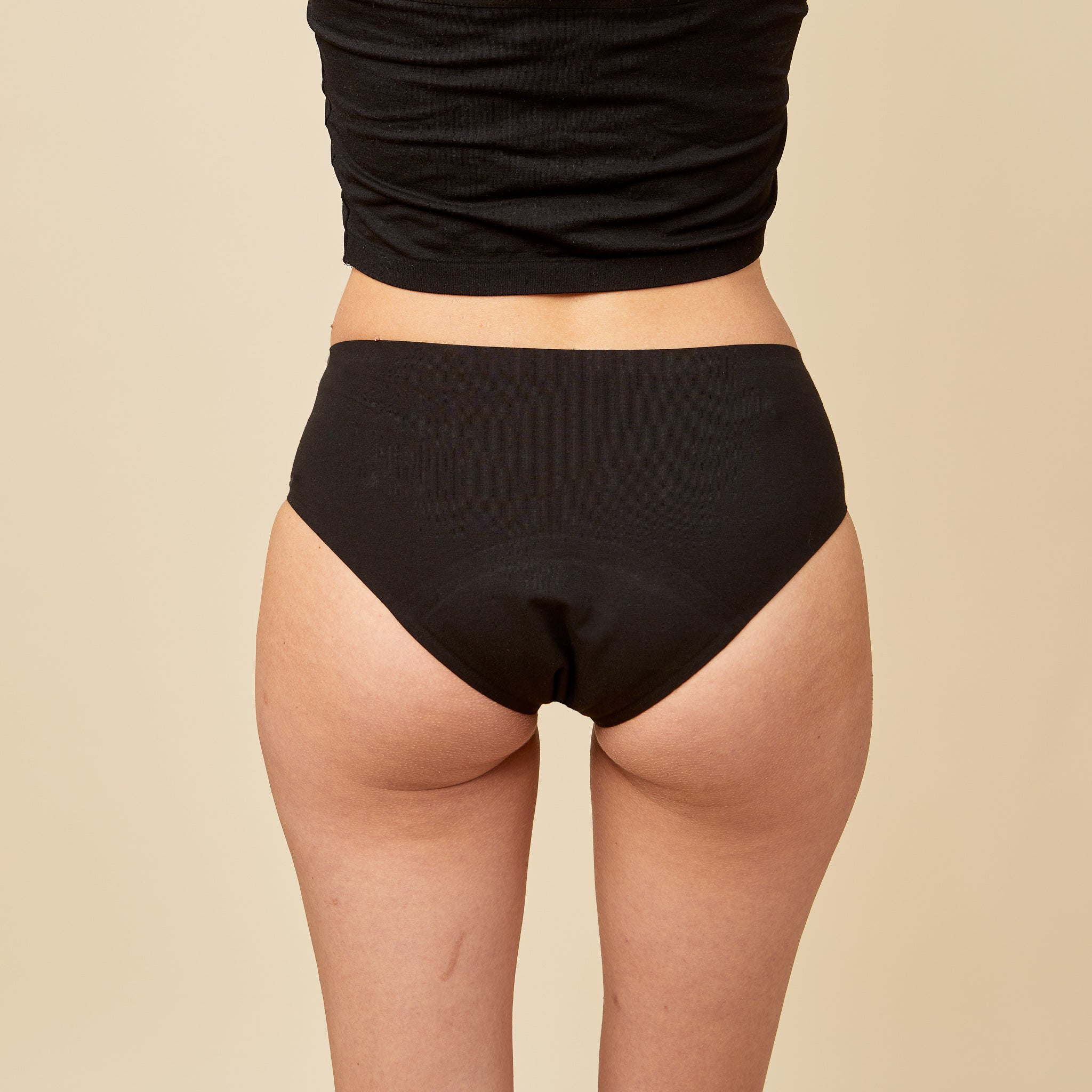  dais period underwear, black, seamless, leak proof, shaping, organic cottondais period underwear hipster in black made of organic cotton worn by a model shown from the back. Super absorbency of up to 4 tampons of blood.